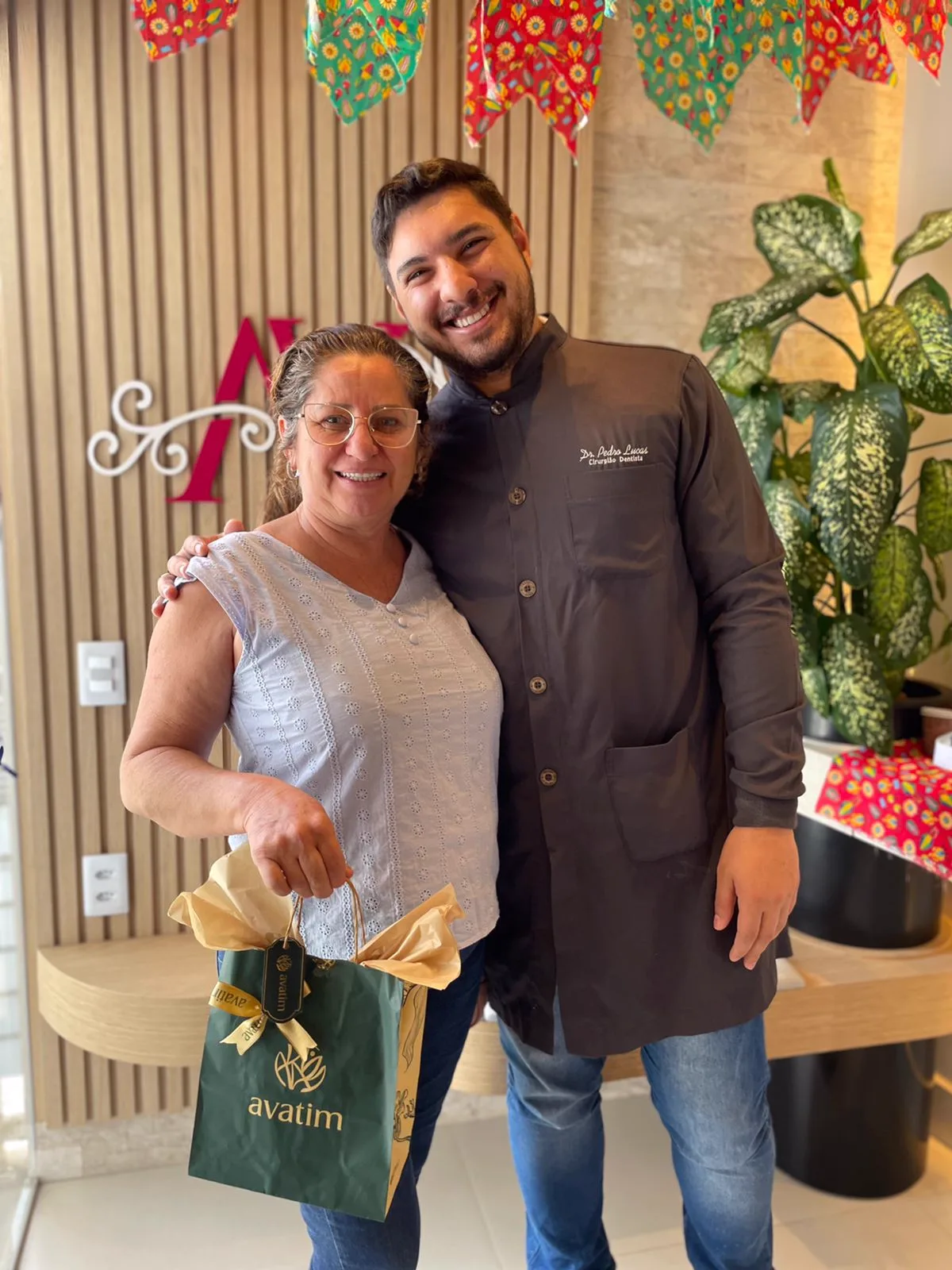 Paciente sorrindo abraçada pelo dentista da clínica