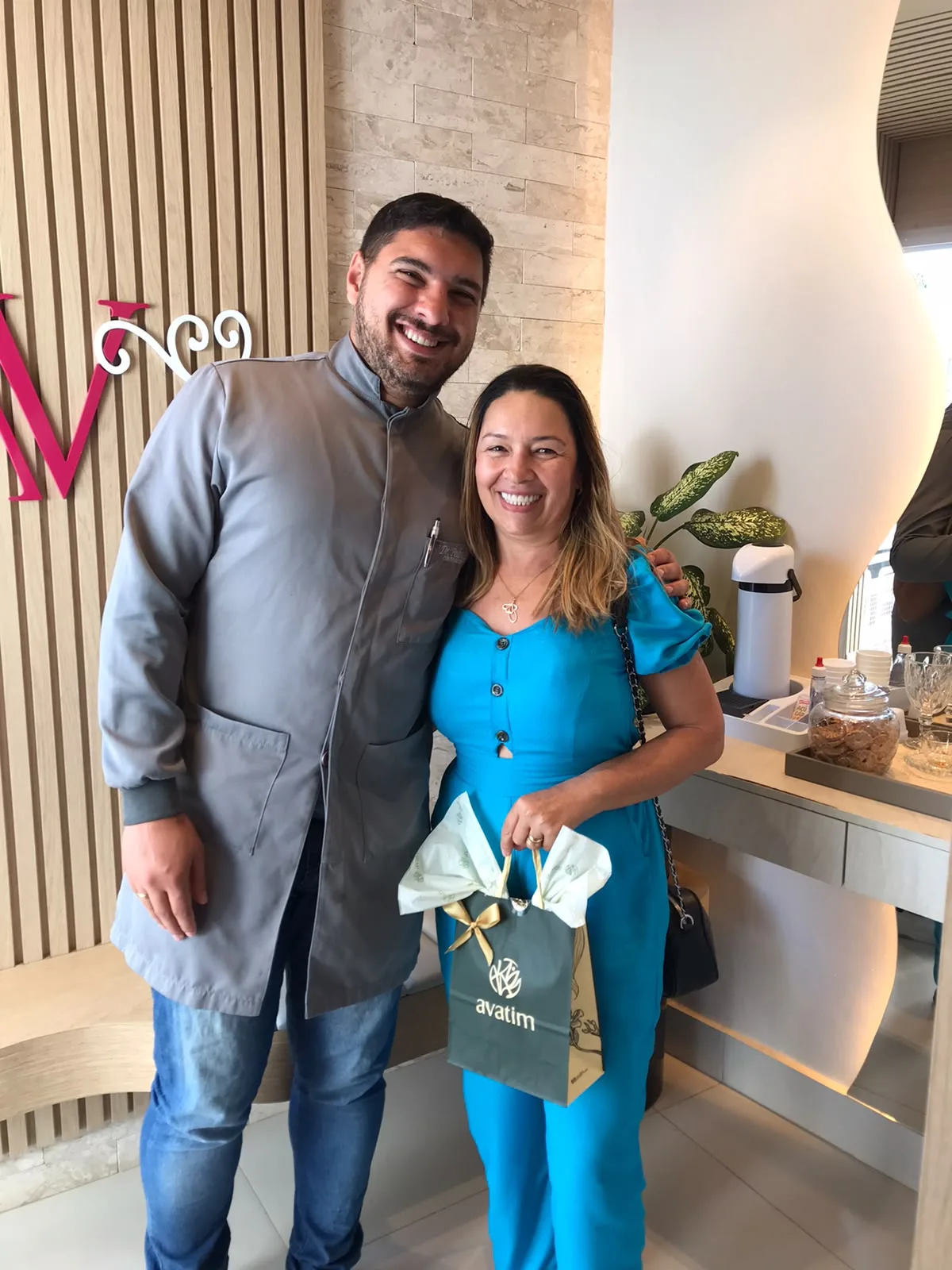 Paciente sorrindo abraçada pelo dentista na recepção da clínica