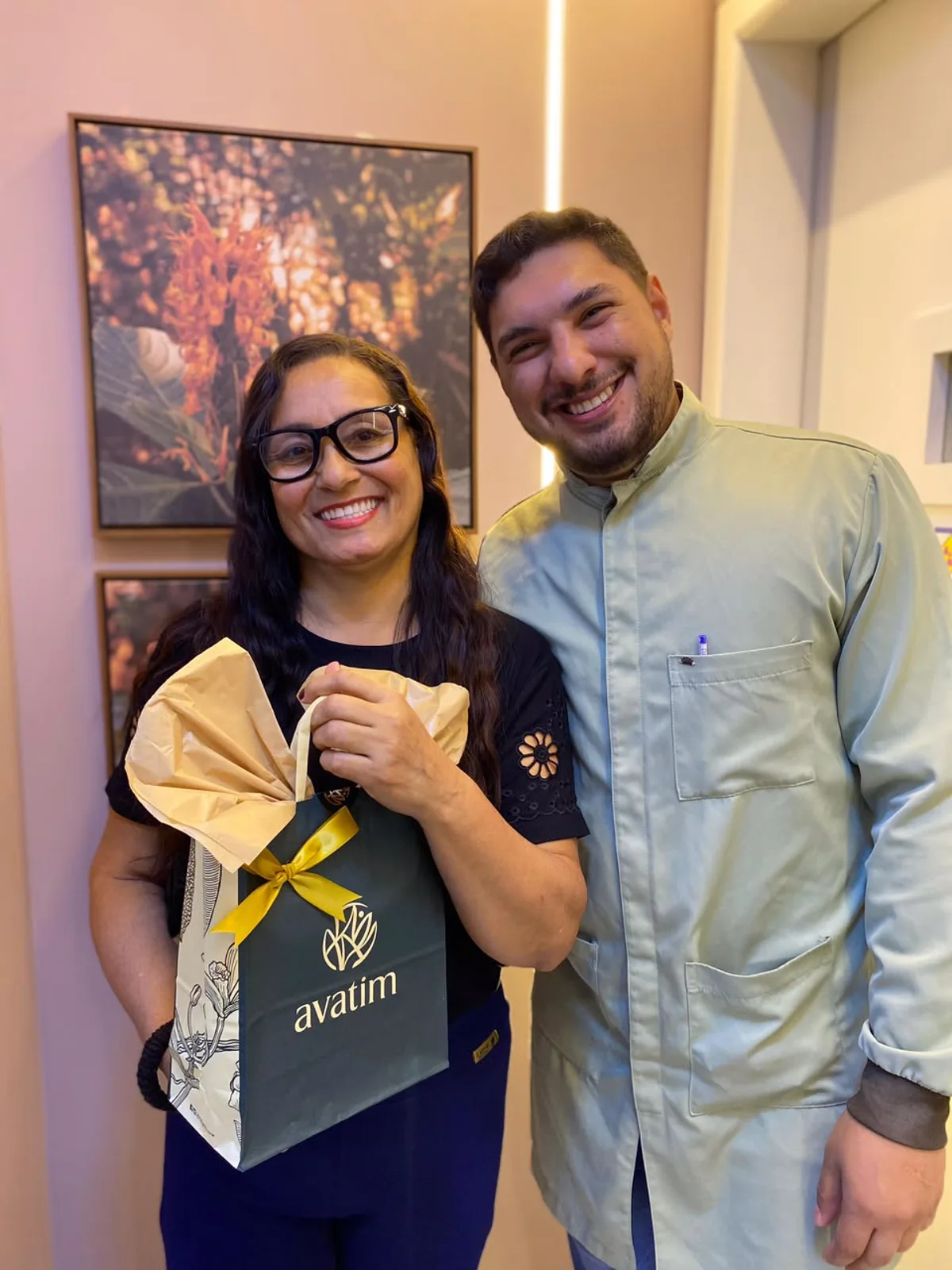Paciente sorrindo ao lado do dentista, com presente da clínica