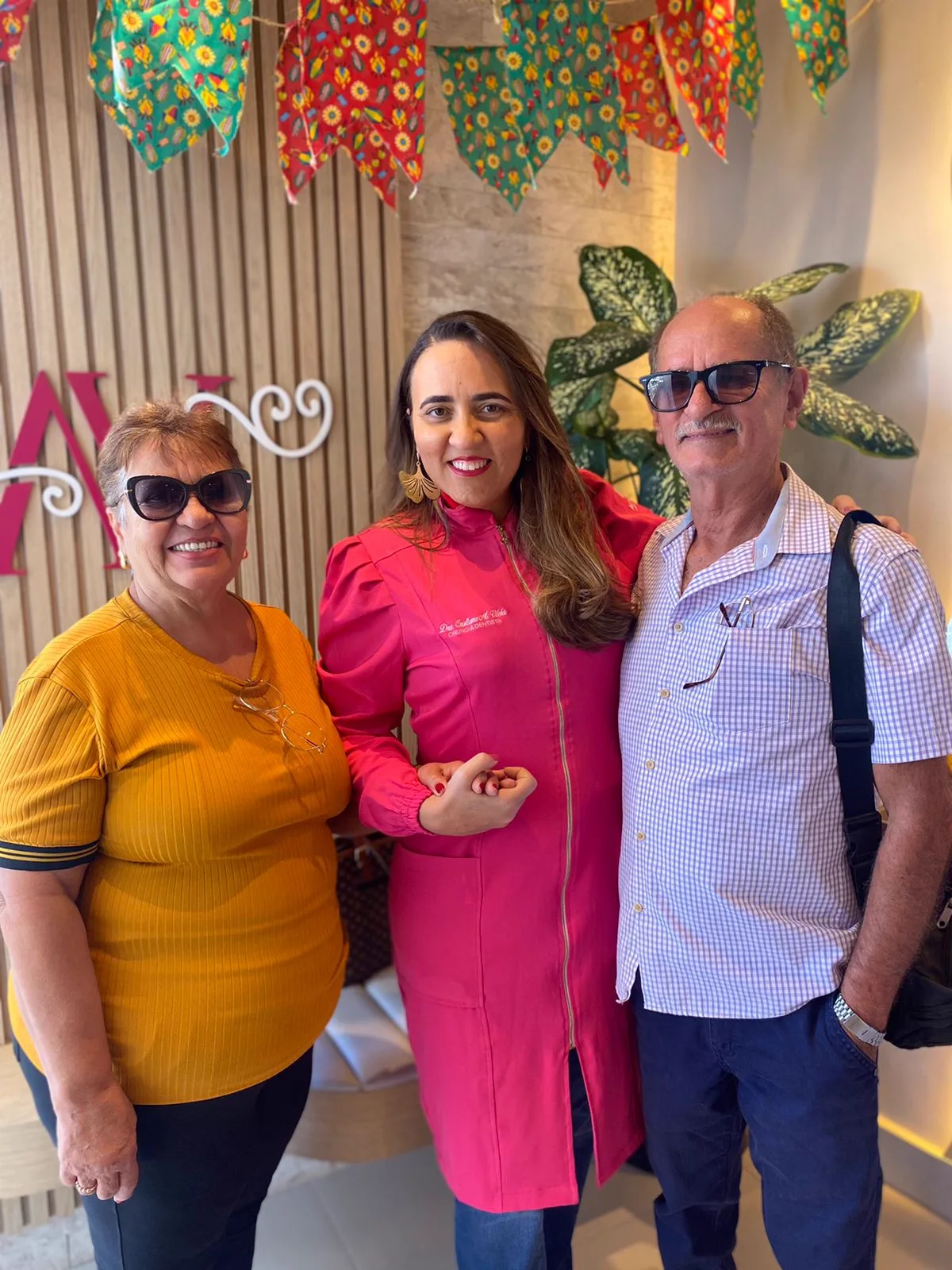 Casal de pacientes sorrindo ao lado da dentista da clínica